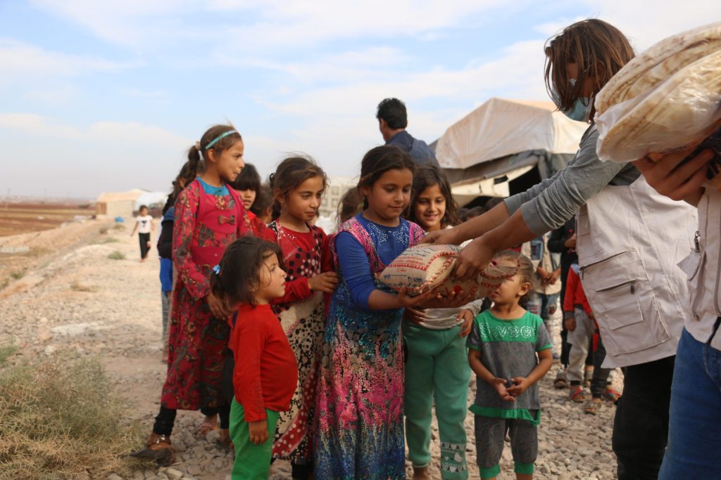 Children receiving bread from an aid worker in a refugee camp