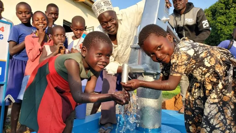 Children drinking clean water from a new well in Uganda