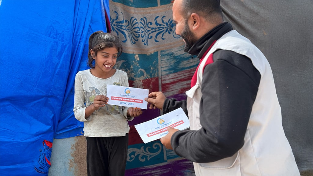 Girl receiving a voucher from an aid worker at her tent