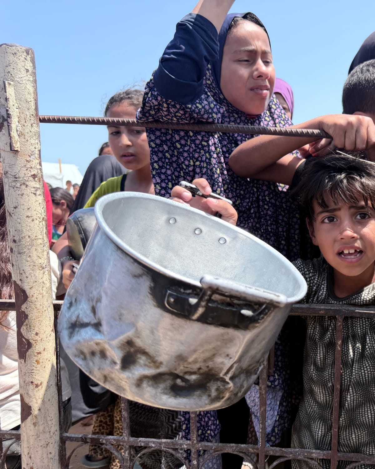 Children waiting with pots for a hot meal in Palestine
