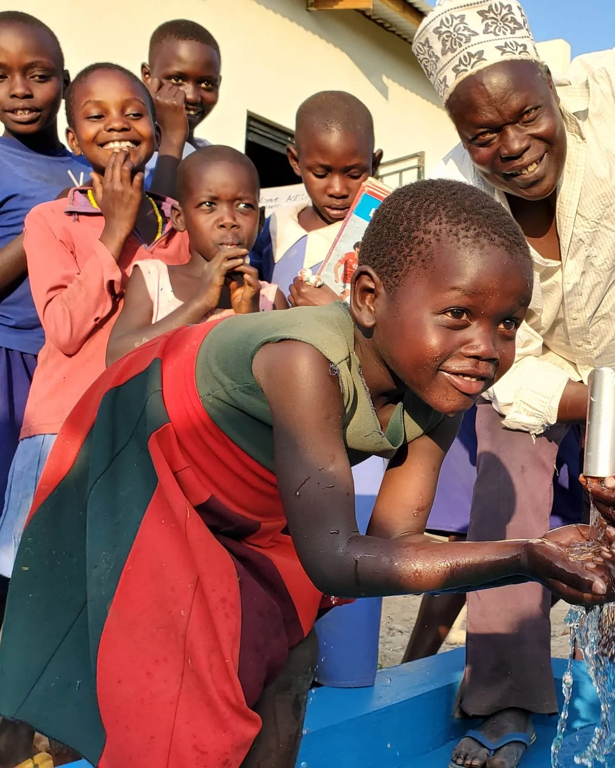 Children drinking clean water from a new well in Uganda