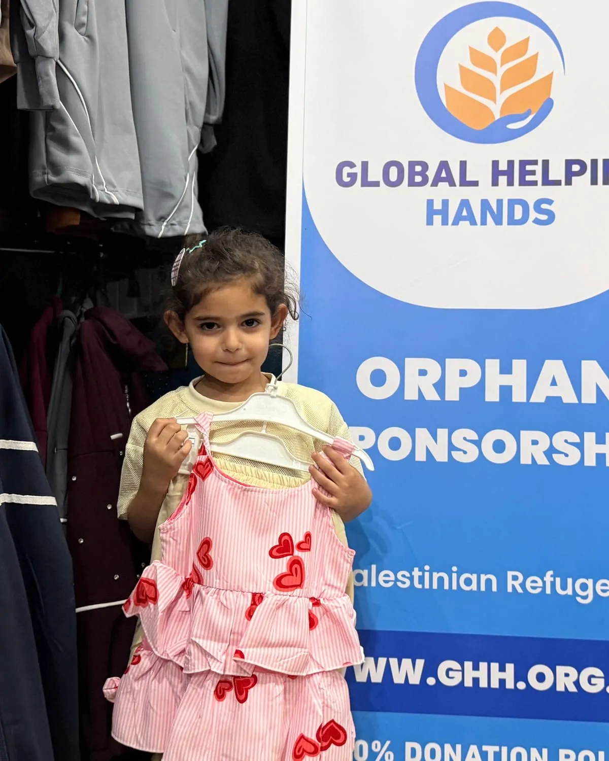 Orphan girl in Palestine holding her new dress from Global Helping Hands Orphan Sponsorship