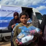 Girl carrying a food parcel from the Global Helping Hands van in Palestine