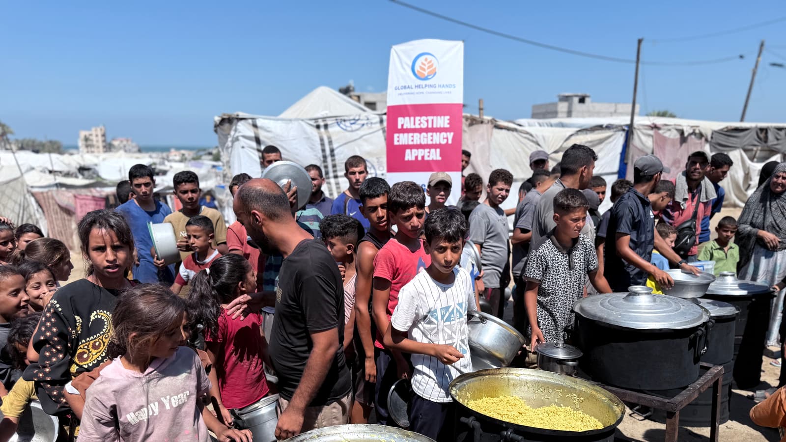 Families queue for hot meals at the Global Helping Hands kitchen in Palestine