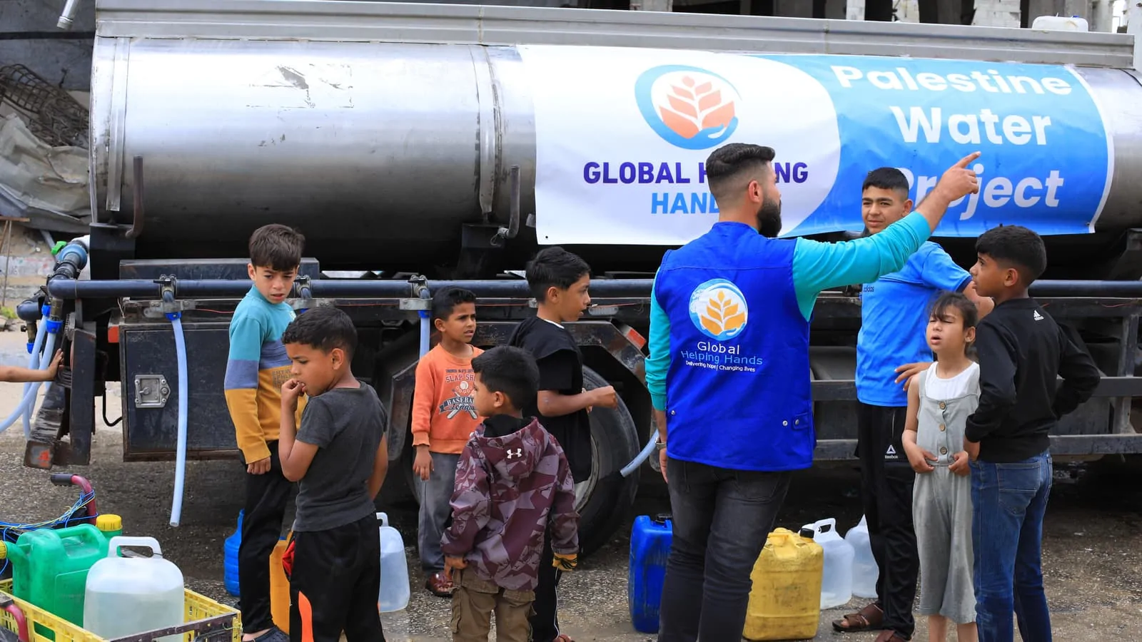 Global Helping Hands worker at the Palestine water tanker with a crowd of children